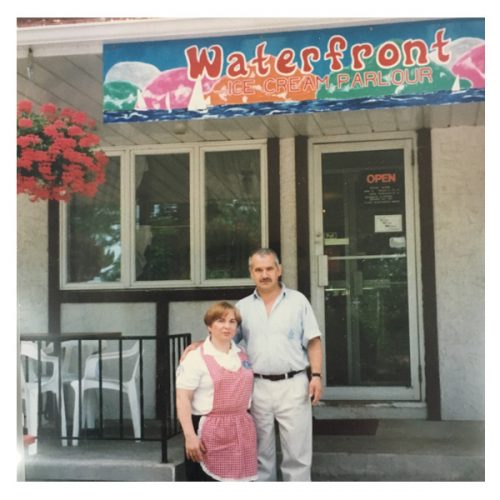 A man and woman standing in front of a restaurant.