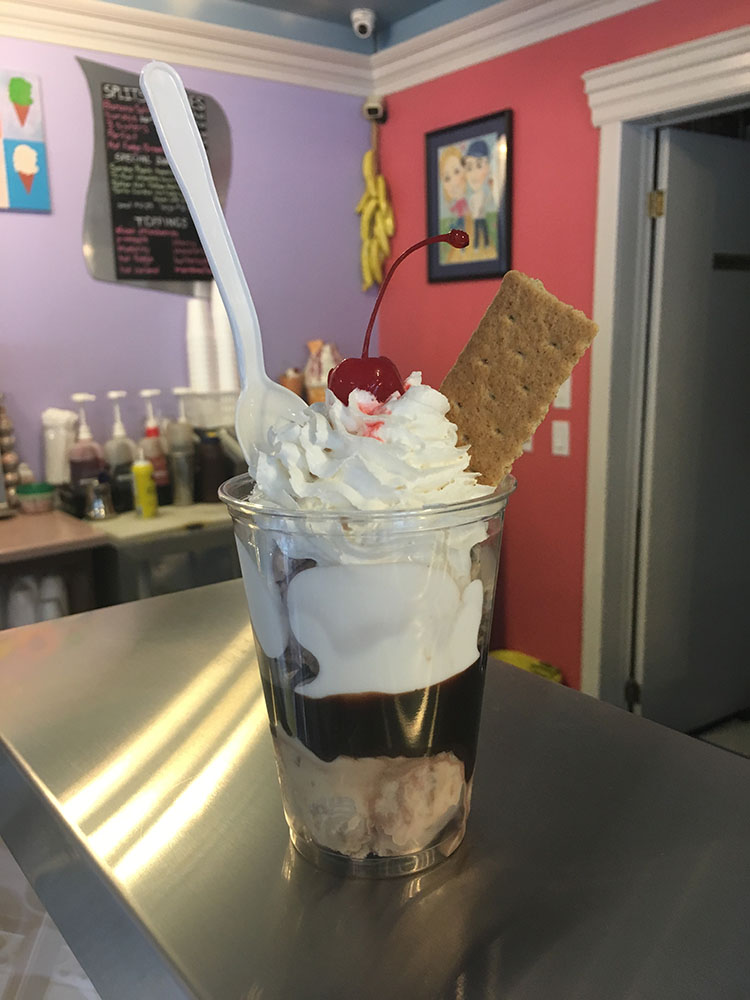 A glass of ice cream with whipped topping and cookies.