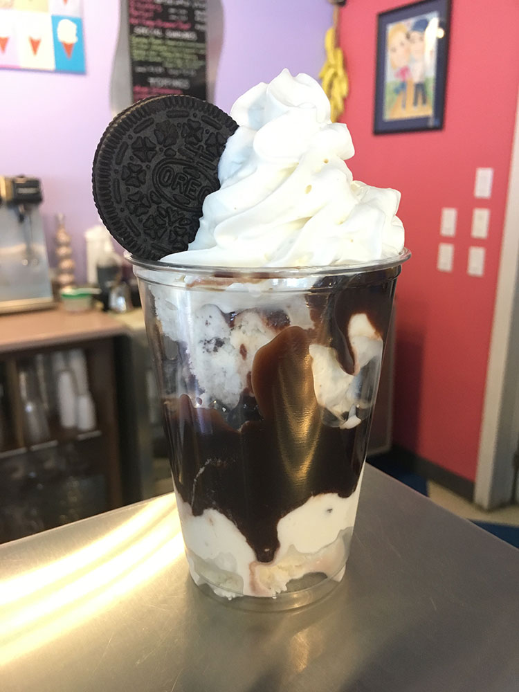 A cup of ice cream and cookies with whipped cream.