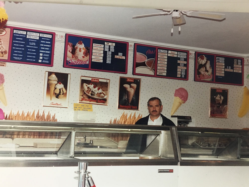 A man standing in front of an ice cream shop.