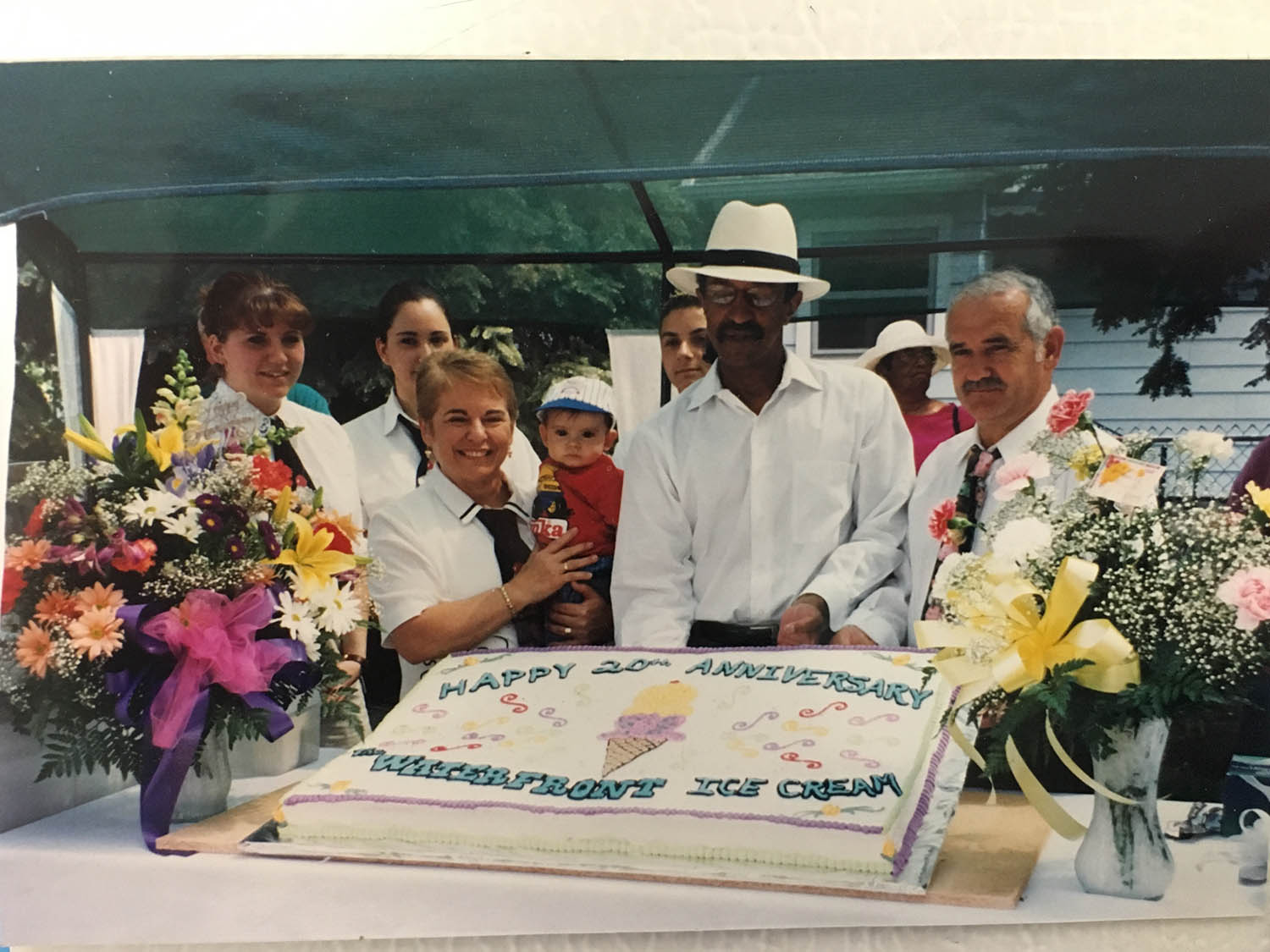 A group of people standing around a cake.