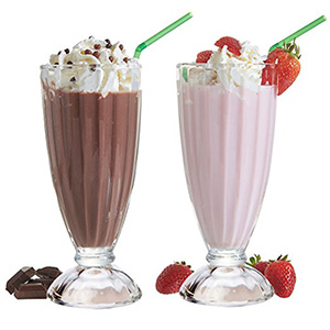 A couple of milkshake cups with some strawberries on top.